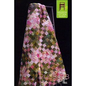 May include: A quilt pattern called "Rhubarb Pie" by Madison Cottage Design. The quilt is made of pink and green fabric squares and is draped over a wooden ladder.