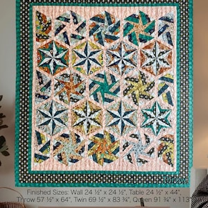 May include: A colorful quilt with a starburst pattern, featuring teal, orange, and yellow geometric shapes on a pink background. The quilt has a black and white polka dot border and a teal edge. The text "Midnight Hex" and "Snapdragon Quilting" are visible.