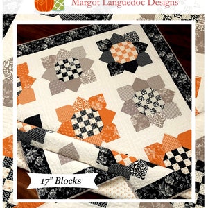 May include: A quilt pattern for a sunflower quilt with 17 blocks. The quilt is made with black, white, orange, and gray fabric. The quilt is called "Sunflowers" and is available from The Pattern Basket.