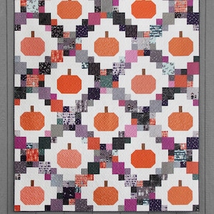 May include: A quilt pattern featuring a patchwork design with orange pumpkins on a white background. The pattern is called "Pumpkin Patches" and is made with fat quarters, 5-inch squares, or 10-inch squares.