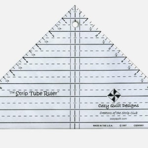 May include: A clear plastic triangle ruler with markings in inches, labeled "The Strip Tube Ruler" and "Cozy Quilt Designs".