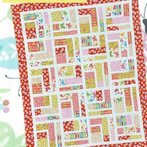 May include: A quilt pattern featuring a patchwork design with a variety of colorful fabrics. The quilt is made up of 10 fat quarters and 2 contrast yards. The pattern is called "Bundle of 10" and is by Amelie Scott Designs. The text "Rotate the blocks to make new layouts" is also included.