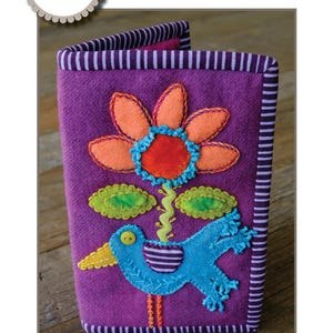 May include: Purple felt needle case with a blue bird, green leaves, and an orange flower appliqué. The case measures 6 1/2 inches by 8 1/2 inches.