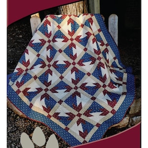 May include: A handmade quilt with a starburst pattern in red, white, and blue. The quilt measures 70" x 70" and is designed by Deb Heatherly. The text "DEB'S CATS N QUILTS Presents: Ruby" is also visible.