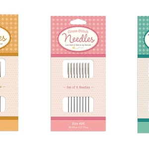 Puede incluir: Tres paquetes de agujas de punto de cruz, cada uno con un fondo de color diferente: naranja, rosa y turquesa. Cada paquete contiene un juego de 8 agujas y est&aacute; etiquetado con el tama&ntilde;o de las agujas: #24, #20 y #28. El texto en los paquetes dice "Agujas de punto de cruz".
