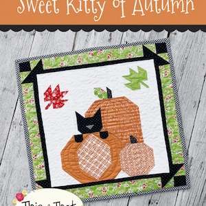 May include: A quilted square featuring a black cat sitting on an orange pumpkin, with two other pumpkins and fall leaves. The quilt has a green floral border and the text "Sweet Kitty of Autumn" is at the top.