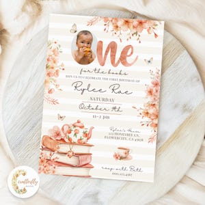 Puede incluir: Una invitación personalizada con foto de bebé, detalles florales y el texto "One for the books". La invitación incluye detalles para una celebración de primer cumpleaños, con una ilustración de tetera y libros.