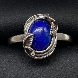 May include: A silver ring with a blue gemstone set in a decorative floral design.