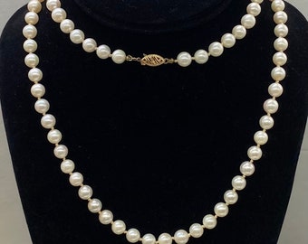 May include: A strand of white pearls with a gold clasp. The pearls are strung on a thin gold chain.
