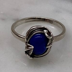 May include: A silver ring with a blue oval-shaped stone set in a delicate silver leaf design.