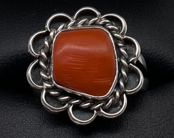 May include: A silver ring with a coral stone set in a flower-shaped design.