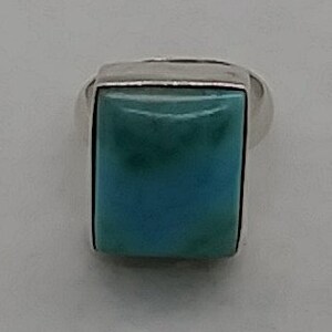 May include: A silver ring with a large, rectangular turquoise stone.