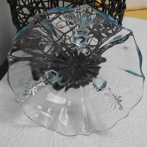 May include: A clear, light blue glass serving dish with a ruffled edge. The dish features decorative hexagonal accents and floral etchings. The dish is likely vintage and suitable for serving desserts or appetizers.