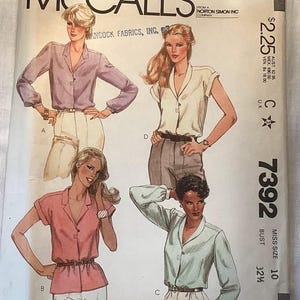 May include: A McCall's sewing pattern envelope, number 7392, featuring illustrations of four different shirt styles. The shirts include long-sleeved and short-sleeved options with collars and button-front closures. The text includes McCall's, 7392, and Miss Size 10.
