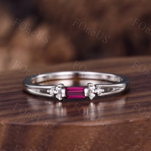 May include: A delicate silver ring with a rectangular ruby gemstone and small diamonds on either side.