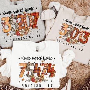 May include: Three sweatshirts with the text "Home sweet home" and different postcode designs. The postcodes are in a fall-themed design with floral accents. The cities of Birmingham, Nashville, and Quinlan are printed below.
