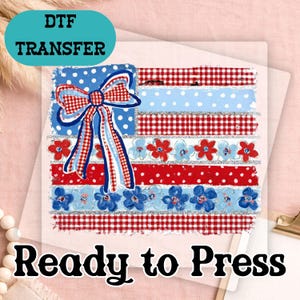 May include: DTF transfer featuring a patriotic design. The design includes a bow, flowers, and stripes in red, white, and blue. The text "Ready to Press" is at the bottom, and "DTF TRANSFER" is at the top.