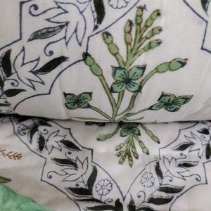 Puede incluir: Tela blanca con un patr&oacute;n repetido de dise&ntilde;os florales negros y azules. La tela presenta un dise&ntilde;o floral verde y marr&oacute;n en el centro.