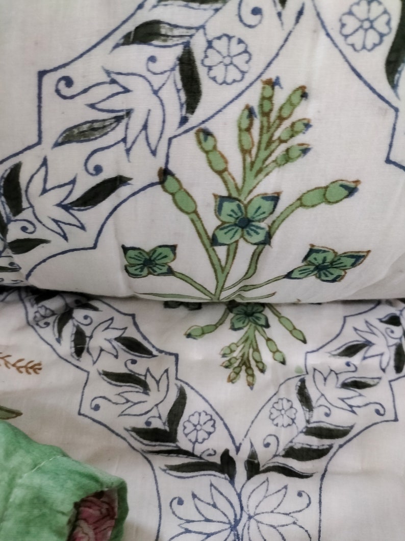 Puede incluir: Tela blanca con un patr&oacute;n repetido de dise&ntilde;os florales negros y azules. La tela presenta un dise&ntilde;o floral verde y marr&oacute;n en el centro.