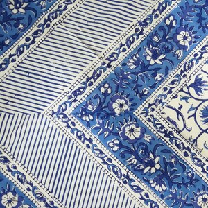 May include: A blue and white patterned textile featuring floral and striped designs. The fabric has a diagonal layout with alternating sections of stripes and floral motifs. The color palette includes shades of blue and white.