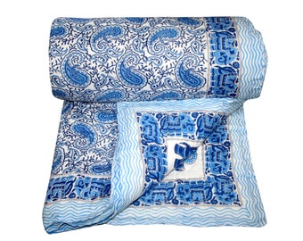 May include: A blue and white cotton quilt with a paisley pattern. The quilt is rolled up and has a decorative border with a blue and white elephant design.