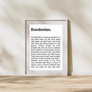 May include: A framed print featuring the word "Dundonian" and a definition. The text describes a Dundonian as someone shaped by a city that never sits still, known for their straight talk, fast wit, and resilience.