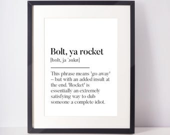 Op de afbeelding: Zwart ingelijste print met de tekst "Bolt, ya rocket" in zwarte letters op een witte achtergrond. De print bevat een definitie van de zin. Een humoristisch stukje wandkunst.