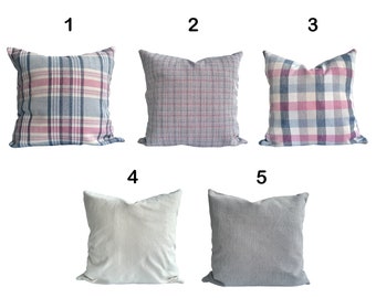 May include: Five decorative throw pillows with different patterns. The pillows are arranged in a row from left to right, numbered 1 through 5. Pillows 1, 2, and 3 have a plaid pattern in shades of blue, pink, and white. Pillows 4 and 5 are solid colours, one white and one grey.