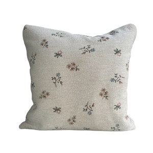 May include: A beige throw pillow with a floral pattern in shades of brown, blue, and green.