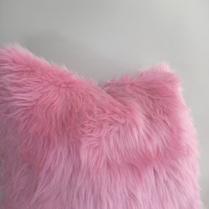 Puede incluir: Una almohada de piel sint&eacute;tica rosa suave con una textura esponjosa.