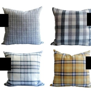 Op de afbeelding: Vier decoratieve kussens met ruitjespatronen. De kussens zijn in tinten grijs, blauw, beige en geel.