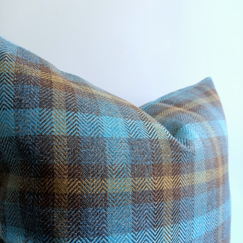 Puede incluir: Una almohada con estampado azul y marr&oacute;n con tejido de espiga.