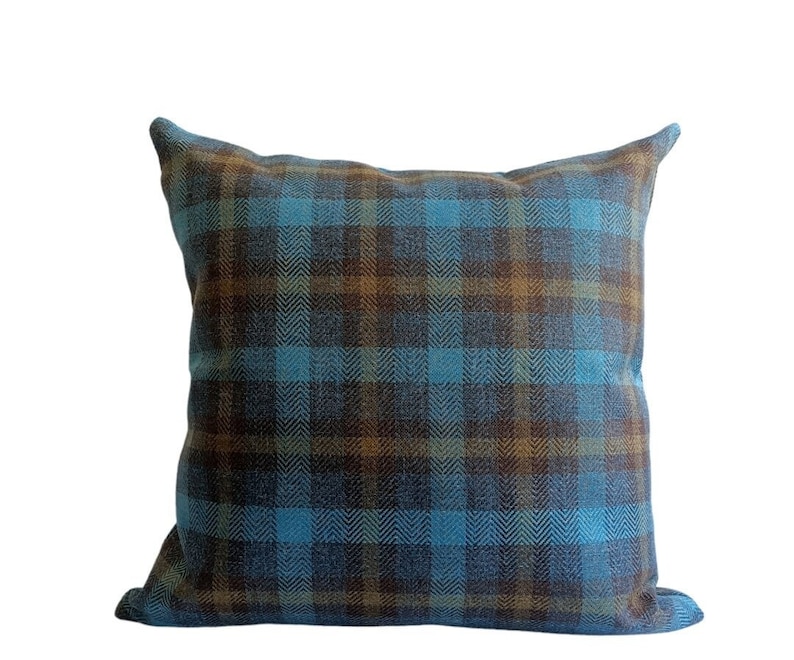 Puede incluir: Una almohada de tiro de cuadros azules y marrones con un patr&oacute;n de espiga.