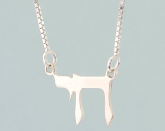 Può includere: Una collana con catena d'argento con un ciondolo d'argento a forma della lettera ebraica Chai.