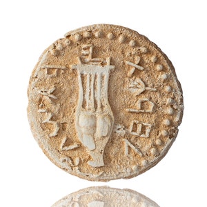 Puede incluir: Primer plano de una moneda antigua con una imagen en relieve de una lira y una inscripción alrededor del borde.