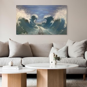 Puede incluir: Una pintura que representa una gran ola rompiendo sobre un grupo de personas que caminan por un sendero en el agua. La pintura está enmarcada y colgada en una pared sobre un sofá gris claro con dos mesas de café blancas.