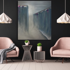 Puede incluir: Dos sillones rosas con una manta gris en uno, frente a frente en una habitación con una pared negra y un suelo blanco. Una pintura de dos cascadas azules con acentos rosas cuelga de la pared. Dos mesas auxiliares de metal dorado con plantas en la parte superior están entre las sillas.