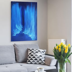 Puede incluir: Un sofá gris con un cojín de patrón blanco y negro, una mesa de café negra con dos tazas de café y un jarrón de tulipanes amarillos.