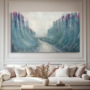 Puede incluir: Pintura abstracta de una ola azul y verde con acentos rosados. La ola se representa como una fuerza poderosa de la naturaleza, con una sensación de movimiento y energía. La pintura está enmarcada y colgada en una pared blanca sobre un sofá blanco.