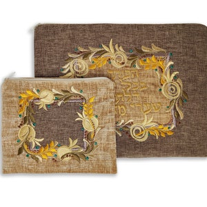 Puede incluir: Dos bolsas de tela marr&oacute;n con dise&ntilde;os florales bordados y texto en hebreo. La bolsa m&aacute;s grande tiene un dise&ntilde;o floral con el texto en hebreo "Bendito seas t&uacute;, Se&ntilde;or nuestro Dios, Rey del universo, que nos santifica con sus mandamientos y nos ordena dedicarnos al estudio de la Tor&aacute;."