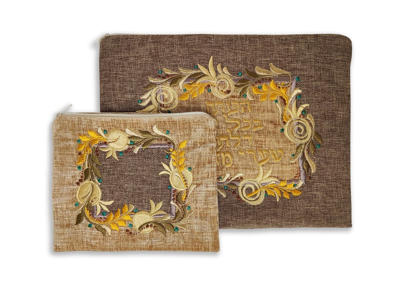 Puede incluir: Dos bolsas de tela marr&oacute;n con dise&ntilde;os florales bordados y texto en hebreo. La bolsa m&aacute;s grande tiene un dise&ntilde;o floral con el texto en hebreo "Bendito seas t&uacute;, Se&ntilde;or nuestro Dios, Rey del universo, que nos santifica con sus mandamientos y nos ordena dedicarnos al estudio de la Tor&aacute;."
