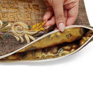 Puede incluir: Una bolsa de cremallera marr&oacute;n con un dise&ntilde;o bordado en oro y un forro de sat&eacute;n dorado. La bolsa est&aacute; abierta y el tirador de la cremallera es visible.