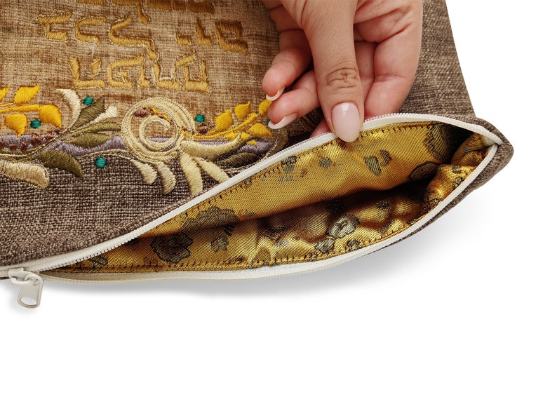 Puede incluir: Una bolsa de cremallera marr&oacute;n con un dise&ntilde;o bordado en oro y un forro de sat&eacute;n dorado. La bolsa est&aacute; abierta y el tirador de la cremallera es visible.