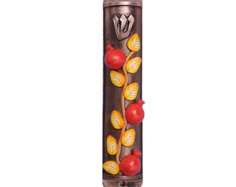 May include: A brown wooden mezuzah case with a decorative design of a pomegranate vine with red pomegranates and yellow leaves. The case has a silver crown on top.