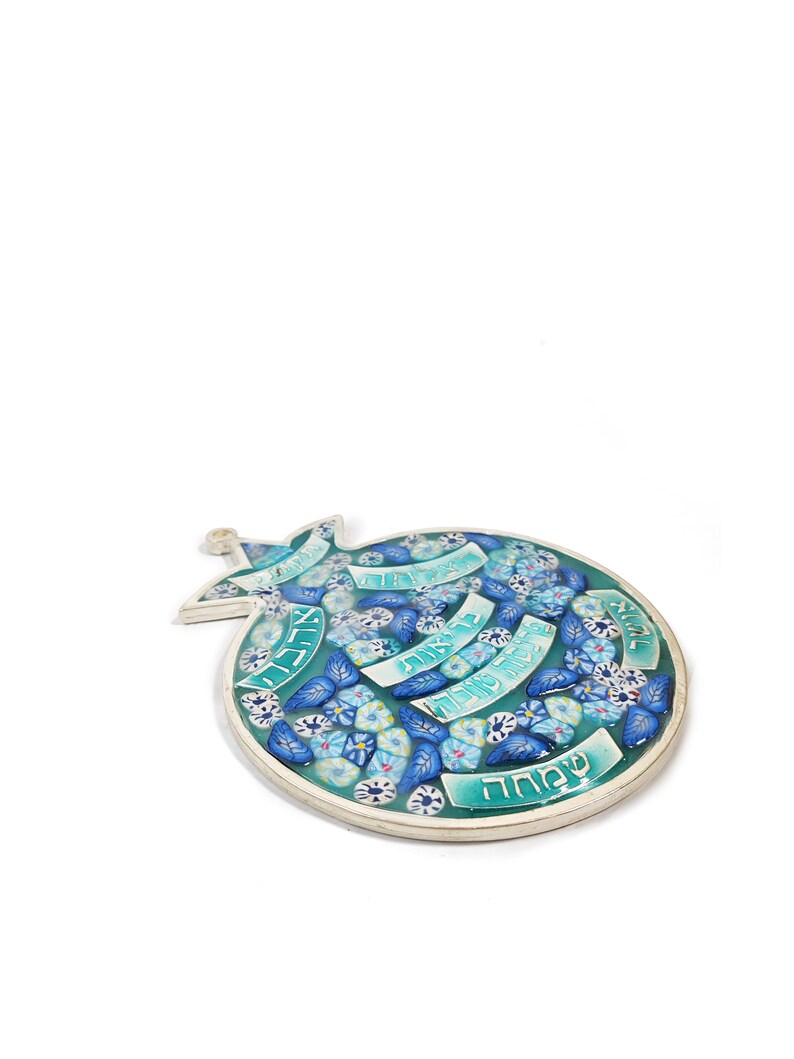 K&ouml;nnte beinhalten: Eine blaue und wei&szlig;e Keramikgranate mit hebr&auml;ischem Text und floralen Designs. Der Granatapfel ist ein Symbol f&uuml;r F&uuml;lle und Wohlstand in der j&uuml;dischen Kultur.
