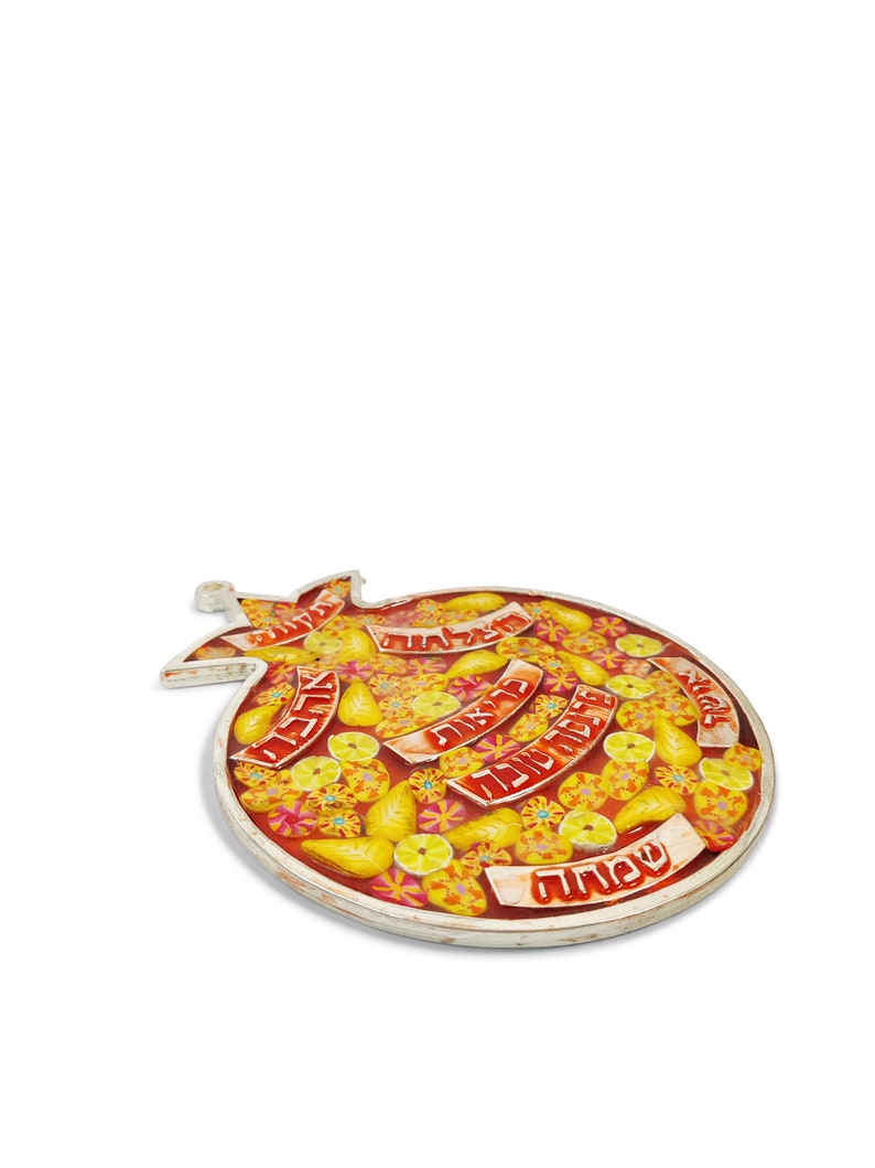 K&ouml;nnte beinhalten: Ein roter und gelber Keramik-Granatapfel-Anh&auml;nger mit hebr&auml;ischem Text und einem floralen Design. Der Anh&auml;nger ist mit gelben Zitronen und Blumen verziert.
