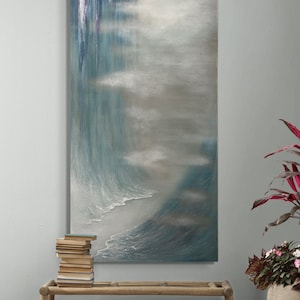 Puede incluir: Una gran pintura abstracta con una gama de colores azules y grises. La pintura representa una ola rompiendo en una playa con un fondo brumoso.