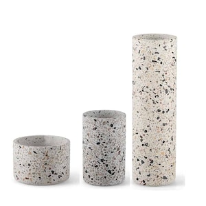 May include: Three terrazzo planters in different sizes. The largest planter is a cylinder, the middle planter is a cylinder, and the smallest planter is a bowl. All three planters are made of a light gray terrazzo with brown, black, and white flecks.