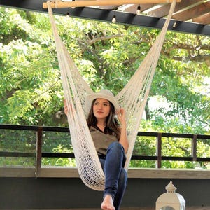 woman sitting on a woven cotton ropw hammock chair swing on a patio
