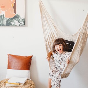 little girl sitting on a hammock chair in a bedroom